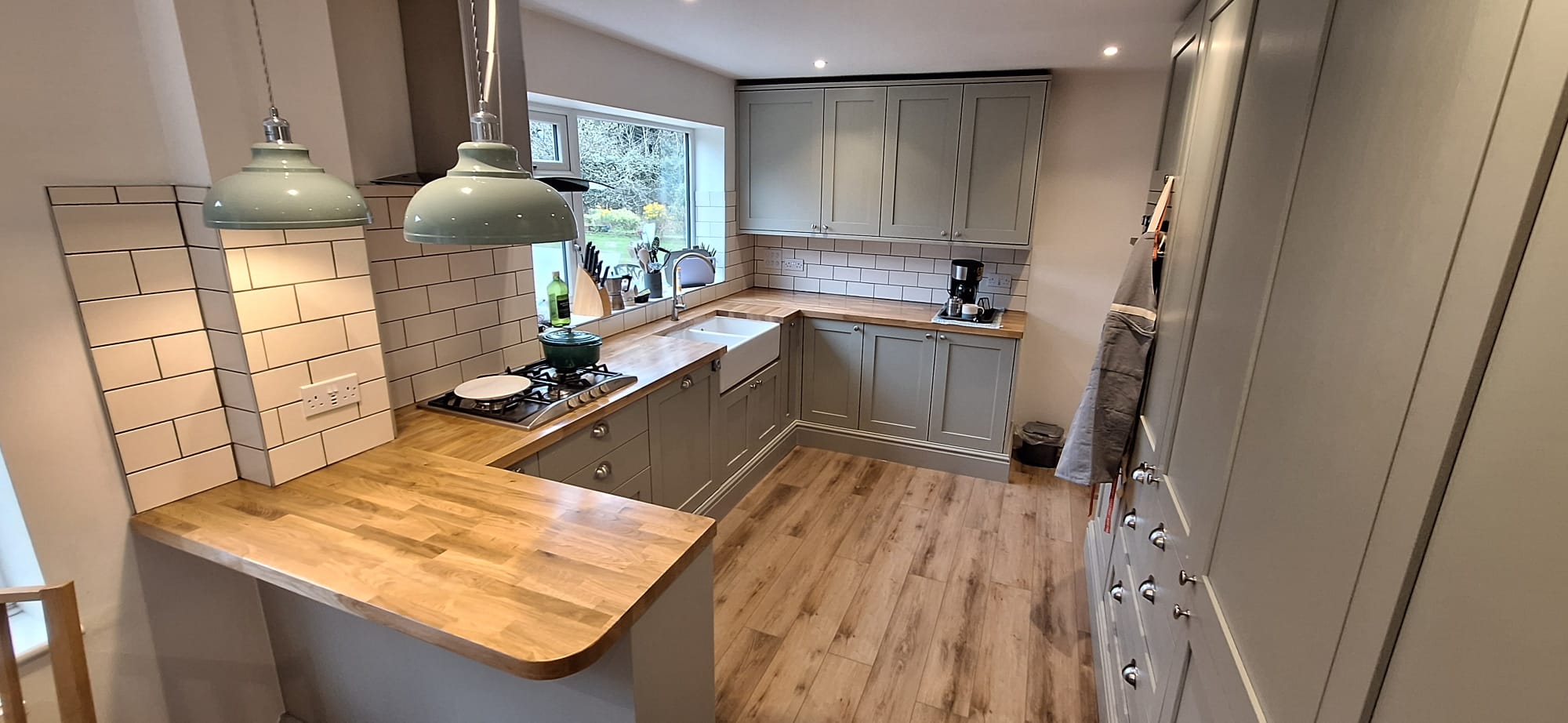Shaker kitchen cabinetry viewed across the oak breakfast bar